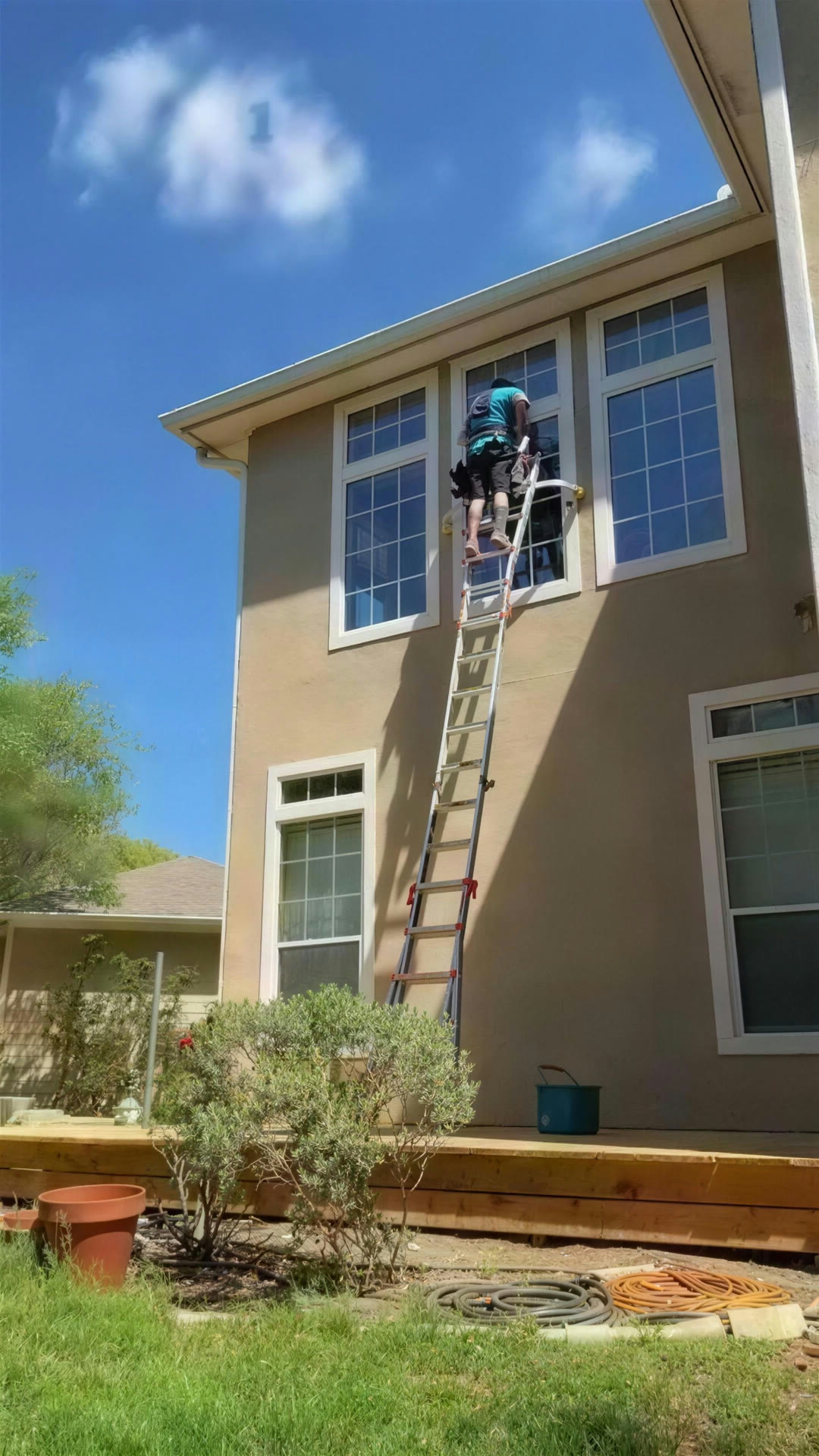 Two-story stucco home, upstairs glass by ladder