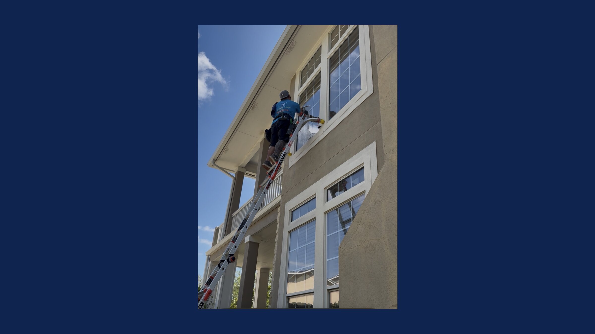 Jerry from J&N Window Cleaning on a ladder cleaning second-story windows on a stucco home in San Antonio